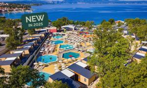 奈维斯Aminess Style Camping Atea Glamping & Holiday Homes的享有带遮阳伞和游泳池的度假村的空中景致