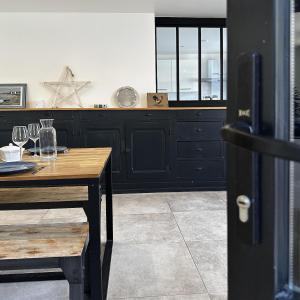 a kitchen with black cabinets and a wooden table at Maison de famille in Courteuil