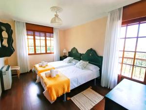 a bedroom with two beds with orange sheets and windows at Casona La Zampuca in Gijón