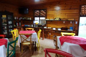 a restaurant with tables and chairs and a kitchen at Monte Carlo Pousada in Olímpia