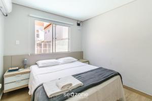 a bedroom with a large bed and a window at Estúdio Modernos em Condomínio com Piscina em Floripa - ASK in Florianópolis