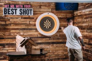 a man standing in front of a wall with a dartboard at Drift Inn at Wyboston Lakes in Saint Neots