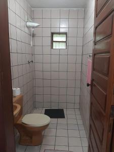 baño de azulejos blancos con aseo y ventana en Casa familiar perto da CEAGA, en Garanhuns