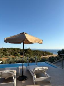 two lounge chairs and an umbrella next to a pool at Villa Sangria in Skala Marion