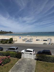 een parkeerplaats met auto's geparkeerd naast een strand bij Appartement Quartier des Mielles Vue mer in LʼIsle-Saint-Cast