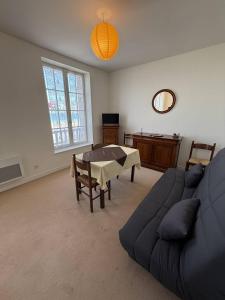 een woonkamer met een blauwe bank en een tafel bij Appartement Quartier des Mielles Vue mer in LʼIsle-Saint-Cast