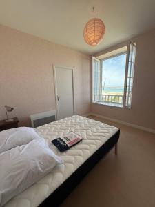 een slaapkamer met een bed met een boek erop bij Appartement Quartier des Mielles Vue mer in LʼIsle-Saint-Cast