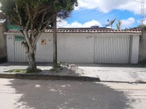 un garaje blanco con un árbol delante en Casa familiar perto da CEAGA, en Garanhuns