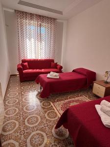 a living room with two beds and a red couch at La CASA DEL SOLE in Paceco