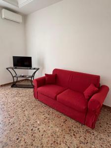 a red couch in a living room with a table at La CASA DEL SOLE in Paceco +18 photos