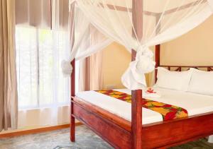 ein Schlafzimmer mit Himmelbett und Fenster in der Unterkunft Cozy Bungalow - Garden, Terrace, Rooftop, Beach in Bwejuu