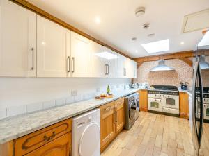 a large kitchen with white cabinets and wooden floors at The Lodge in Gloucester +22 photos