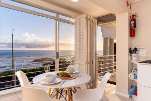 a kitchen and dining room with a table and chairs at Sunset Azure Studio - Pool Views 2 min to beach in Cape Town