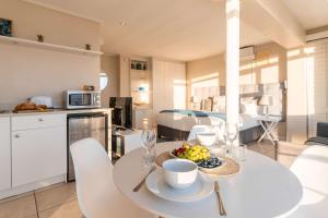 a kitchen and living room with a white table and chairs at Sunset Azure Studio - Pool Views 2 min to beach in Cape Town +8 photos