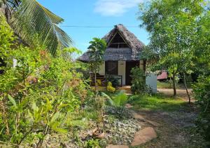 ein kleines Haus mit einem Strohdach in der Unterkunft Cozy Bungalow - Garden, Terrace, Rooftop, Beach in Bwejuu