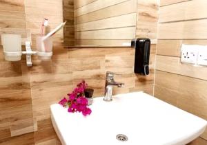 ein Badezimmer mit einem Waschbecken mit Blumen darauf in der Unterkunft Cozy Bungalow - Garden, Terrace, Rooftop, Beach in Bwejuu