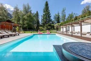 a swimming pool with chairs and a house at Hôtel Les Aiglons Chamonix in Chamonix
