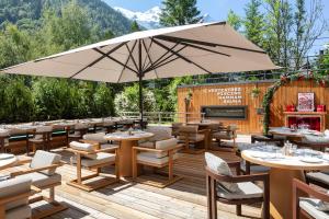 a patio with tables and chairs and an umbrella at Hôtel Les Aiglons Chamonix in Chamonix