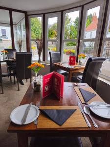 a dining room with tables and chairs and windows at The Queens Inn in St. Martin Guernsey