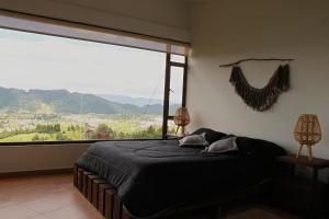 a bedroom with a bed and a large window at Casa finca, descanso en medio de la naturaleza . in Tabio