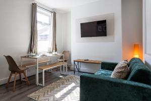 Una sala de estar con un sofá verde y una mesa. en Central Darlington 3 Bedroom Home, en Darlington