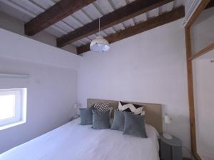a white bedroom with a bed with gray pillows at AmazINN Places Casa Calabuig Ático Marina Real - No Ascensor- in Valencia