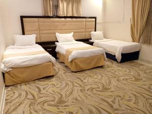three beds in a room with a carpet at مسك روز المنسك للشقق المخدمه in Quai