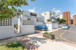 a white building with a car parked in a parking lot at Terrassenzeit 3 in Puerto de la Cruz