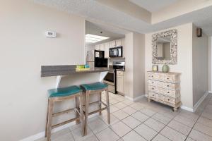 a kitchen with two bar stools and a counter at Beach Club #329 in Saint Simons Island