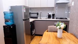 SkyView Haven by Seluveto Homes في نيروبي: مطبخ مع ثلاجة وطاولة مع إناء من الزهور +22 صورة