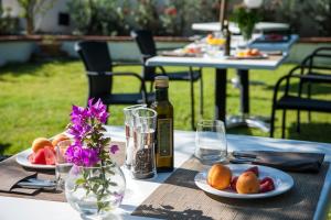 a table with plates of fruit and a bottle of wine at Hotel Baia Del Capitano in Cefalù