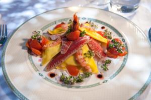 a plate of food with meat and vegetables on a table at Hotel Baia Del Capitano in Cefalù