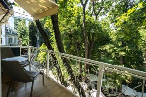 Un balcón con una silla y vista a los árboles. en Moncastro Бутік-готель, en Odessa