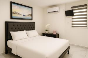 a white bedroom with a white bed and a television at Sunset Suites Mazatlán at Lomas de Mazatlán in Mazatlán +20 photos