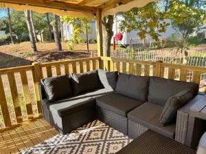 米尼赞海滩KOKUA VACANCES Mobil Homes Résidentiels camping 4 étoiles MIMIZAN PLAGE的带木质甲板的露台上摆放着一张沙发