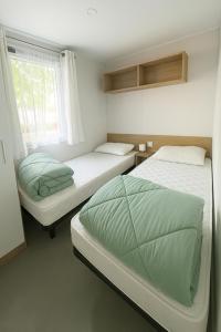 米尼赞海滩KOKUA VACANCES Mobil Homes Résidentiels camping 4 étoiles MIMIZAN PLAGE的有两张床和一扇窗户的房间 更多37张照片