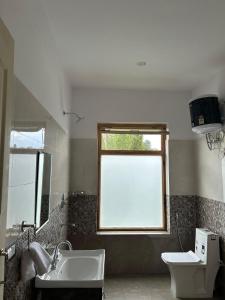 a bathroom with a sink and a window and a toilet at Otsal Villa in Leh +16 photos