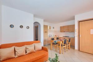 a living room with an orange couch and a kitchen at Apartamento T2 com wifi in Santa Maria
