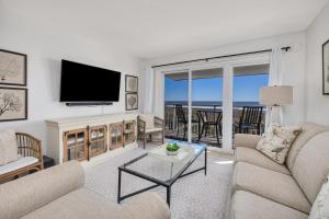 a living room with a tv and a couch and a table at Beach Club #429 in Saint Simons Island