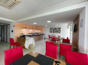 a restaurant with red chairs and a dining room at Beach Class Excelsior - Flat 1 quarto no Pina por Yolo in Recife