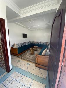 a living room with a blue couch and a tv at Yahya oulidia in Oualidia