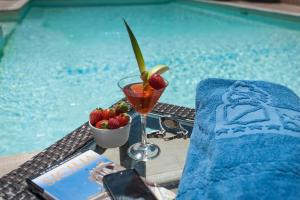 a table with a drink and fruit next to a swimming pool at Hotel Baia Del Capitano in Cefalù