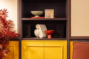 a yellow cabinet with plates and bowls on a shelf at JOIVY Together Florence Secret Nest in Florence