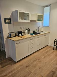 a kitchen with white cabinets and a wooden floor at Grande Sologne in Clémont