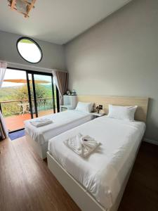 two beds in a room with a large window at Two Tree Cafe At Suanmuangthong 