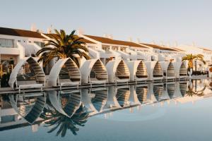 a row of white buildings and a swimming pool at Lago Resort Menorca - Casas del Lago Adults Only in Cala en Bosc
