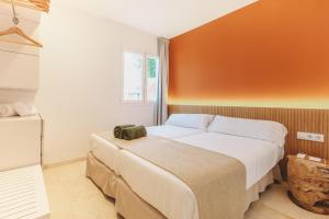 Un dormitorio con una cama grande con una pared naranja. en Lago Resort Menorca - Villas & Bungalows del Lago, en Cala'n Bosch