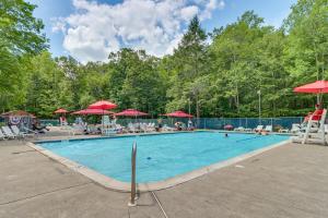 una grande piscina con sedie e ombrelloni rossi di Pool and Lake Access, Yard Poconos Family Getaway a East Stroudsburg