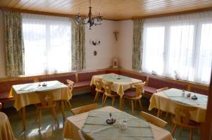 una sala da pranzo con tavoli, sedie e finestre di Haus Dachstein Schnitzer a Eben im Pongau
