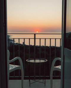 a table and two chairs on a balcony with the sunset at B&B Bellaria Rooms in Longbardi